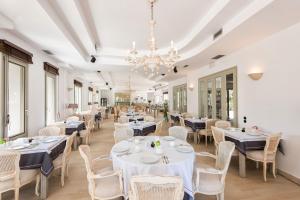 a restaurant with white tables and chairs and a chandelier at Saint Andrea Seaside Resort - Adults Only in Naousa