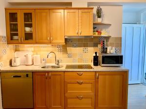 a kitchen with wooden cabinets and a sink and a microwave at Villa Yadranka in Strunjan