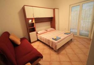 een slaapkamer met een bed en een rode bank bij Apartments Mili - 250 m from sea in Rab