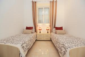 a bedroom with two beds and a window and two lamps at Valletta Triton Apartment in Valletta