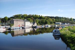 a boat is docked in a river next to a town at Waterside Guesthouse in Graiguenamanagh