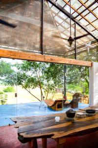 a wooden table in a room with a large window at Seclude Falling Cashews, Chorao Island, North Goa in Chorao