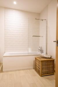 a white bathroom with a tub and a wicker table at Cavernous open plan town house in st Leonards in St. Leonards
