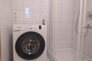 uma máquina de lavar roupa na casa de banho com um chuveiro em TTP Apartment 6 Friedrichshafen em Friedrichshafen