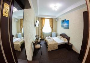 una camera d'albergo con due letti e uno specchio di Oscar Mini Hotel a Sinferopoli