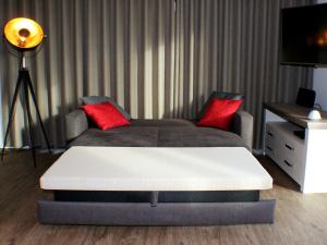 a bed with two red pillows in a room at Mien Dröm im Sielhuus in Butjadingen