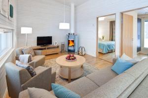 Una sala de estar con un sofá, una mesa y un televisor. en Holiday Club Kuusamon Tropiikki Apartments, en Kuusamo