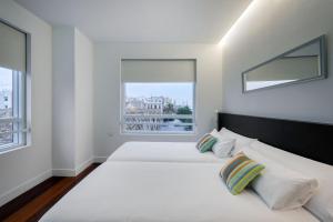 a white bedroom with a large bed and a window at Sea You Hotel Port Valencia in Valencia