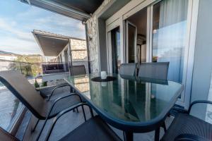 a glass table on the balcony of a house at Nika Apartment in Hanioti