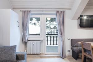 ein Wohnzimmer mit einer Glasschiebetür und einem Balkon in der Unterkunft Cesa Civetta in Canazei