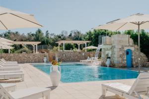 a swimming pool with white chairs and umbrellas at Masseria Muntibianchi AgriResort Restaurant & SPA in Otranto