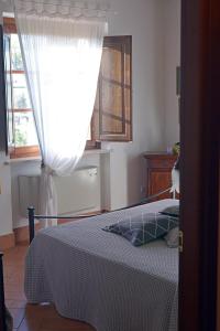 - une chambre avec un lit avec un rideau et une fenêtre dans l'établissement Il Poggio Della Pieve Apartments, à Santa Luce