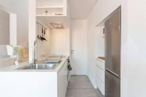 a white kitchen with a sink and a refrigerator at Beautiful Apartment with View of the Tagus River in Lisbon +20 photos