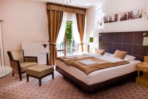 a bedroom with a large bed and a chair at Pałac na wodzie Falkowski Medical & SPA & Conference in Augustów