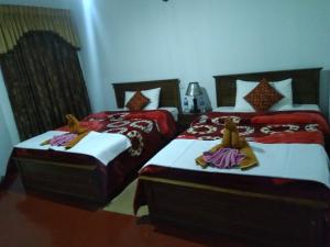 2 Betten in einem Zimmer mit roter und weißer Bettwäsche in der Unterkunft Avon Field Holiday Bungalow in Nuwara Eliya