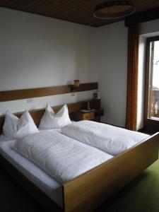 1 dormitorio con 1 cama con sábanas blancas y ventana en Pension Rainhof, en Santa Maddalena in Casies