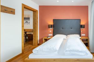 1 dormitorio con 1 cama grande y pared de color naranja en Alphus Appartements, en Warth am Arlberg