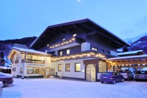 ein großes Gebäude mit Autos auf einem Parkplatz in der Unterkunft Gästehaus Steger in Kaprun