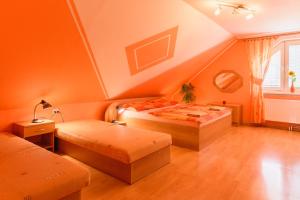 two beds in a room with orange walls at Apartman Elegant in Bešeňová