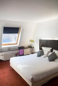 um quarto com uma grande cama branca e uma janela em 55 Hôtel Montparnasse em Paris
