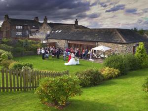 a bride and groom walking down the lawn at a wedding at The White Hart at Lydgate in Oldham