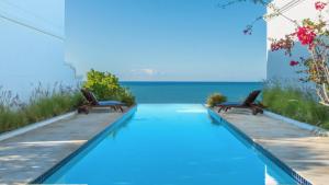 einen Pool mit zwei Stühlen und das Meer in der Unterkunft THE VILLAS at THE HORNED DORSET PRIMAVERA in Rincon