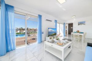 Infinity View Villa في أيا نابا: غرفة معيشة مع ستائر زرقاء ونافذة كبيرة