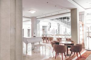 a lobby with a white piano and tables and chairs at Don Plaza Congress Hotel in Rostov on Don