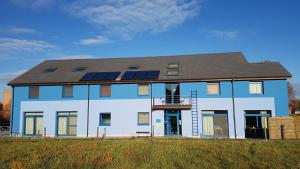 een groot blauw gebouw met zonnepanelen erop bij Hotel Amethist in Ramsel