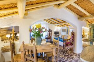 un salon avec une table avec un vase de fleurs dessus dans l'établissement Charming Cottage Il Glicine a San Pantaleo, à San Pantaleo