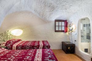 - une chambre avec un lit rouge dans un mur en pierre dans l'établissement Charming Cottage Il Glicine a San Pantaleo, à San Pantaleo