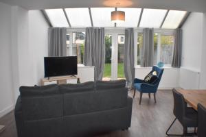 a living room with a black couch and a tv at Four Chimneys House in Peterborough