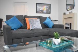 a living room with a black couch with blue and orange pillows at Four Chimneys House in Peterborough