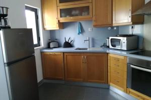 uma cozinha com armários de madeira e um micro-ondas em Apartamento Varandas Soalheiras em Odeceixe