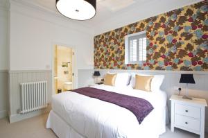 a bedroom with a white bed and a floral wall at 27 The Terrace in St Ives