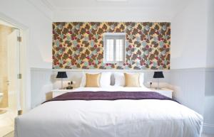a bedroom with a white bed with a floral wallpaper at 27 The Terrace in St Ives