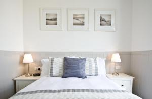 a bedroom with a white bed with three pictures on the wall at 27 The Terrace in St Ives