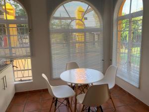 a kitchen with a white table and chairs and windows at One More Nap Self Catering in Bloemfontein