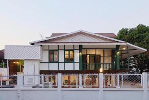 a house with a white fence in front of it at Barn Laos Hostel in Vientiane