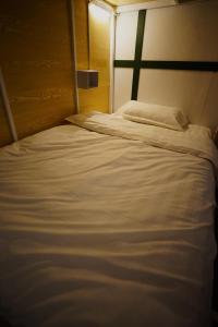 a large white bed in a small room at Barn Laos Hostel in Vientiane