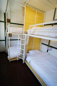two bunk beds in a room with white sheets at Barn Laos Hostel in Vientiane