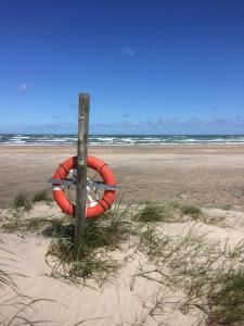 un salvavidas rojo está sentado en la playa en Sejtræk Apartments, en Tversted