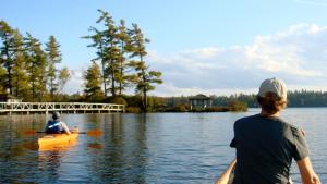 um homem e uma mulher num caiaque num lago em White Pine Camp em Paul Smiths