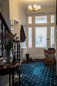 ein Zimmer mit einer Treppe und einer Vase auf einem Tisch in der Unterkunft Queensberry House B&B in Moffat