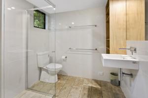 a white bathroom with a toilet and a sink at Pandanus Retreat in Point Lookout