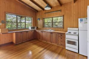 a kitchen with wooden cabinets and a white refrigerator at Alinjarra - 13 Waller Court in Point Lookout