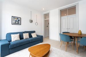 ein Wohnzimmer mit einem blauen Sofa und einem Tisch in der Unterkunft FLH Lx Factory Charming Place in Lissabon