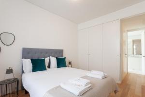 a white bedroom with a large white bed with green pillows at FLH Chiado Central Flat in Lisbon