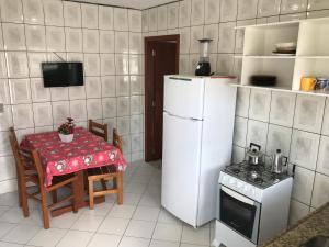 a kitchen with a table and a white refrigerator at Pousada Mera in Florianópolis