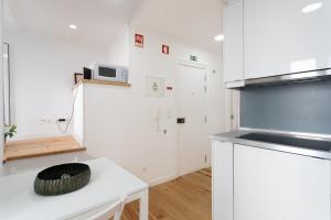 una cucina con armadi bianchi e piano di lavoro bianco di FLH Mouraria Charming Flat II a Lisbona